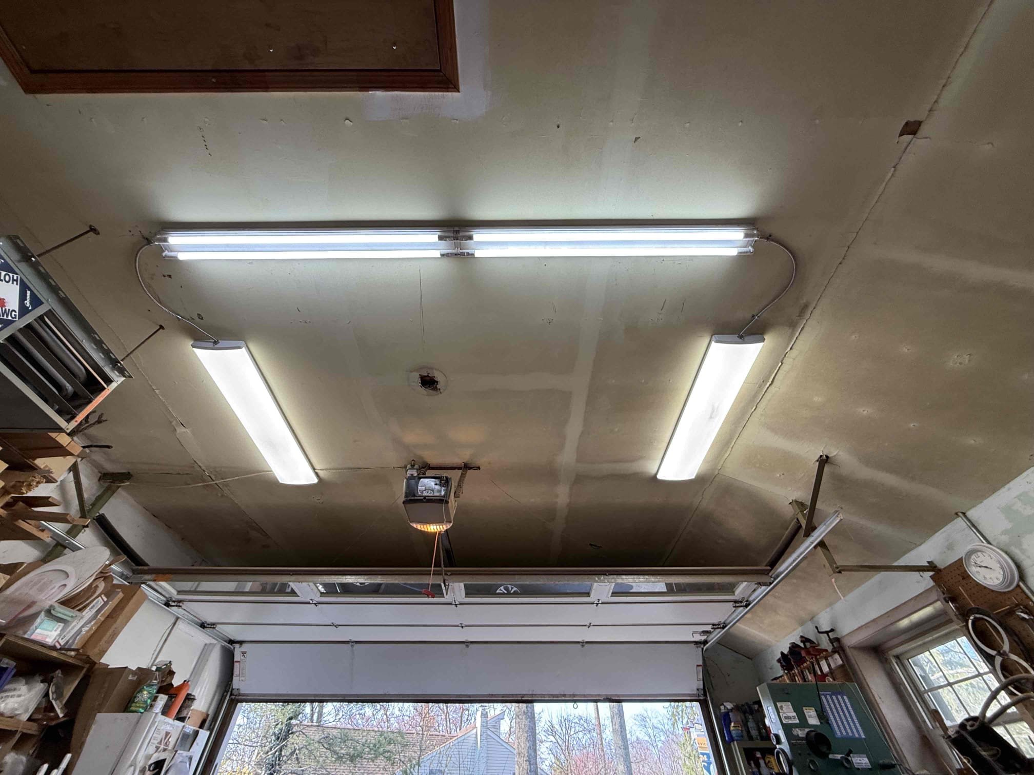 Thomas Edison Electric installed three LED strip light fixtures across the ceiling of a garage in Jenkintown, PA. The bright, evenly spaced lighting provides full coverage for the workspace, a major upgrade over a single bulb setup.