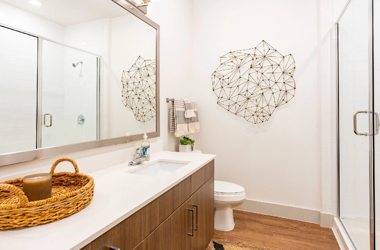 Styled bathroom at The Drake Apartments in Midland, TX featuring quartz countertops, a wood-grain va 