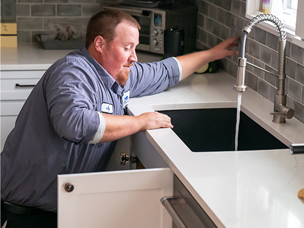 A Done plumber testing a kitchen sink