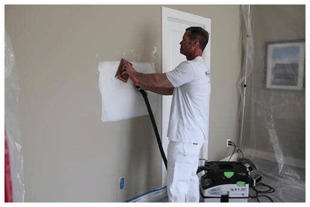 Man using plaster on wall to repair hole.
