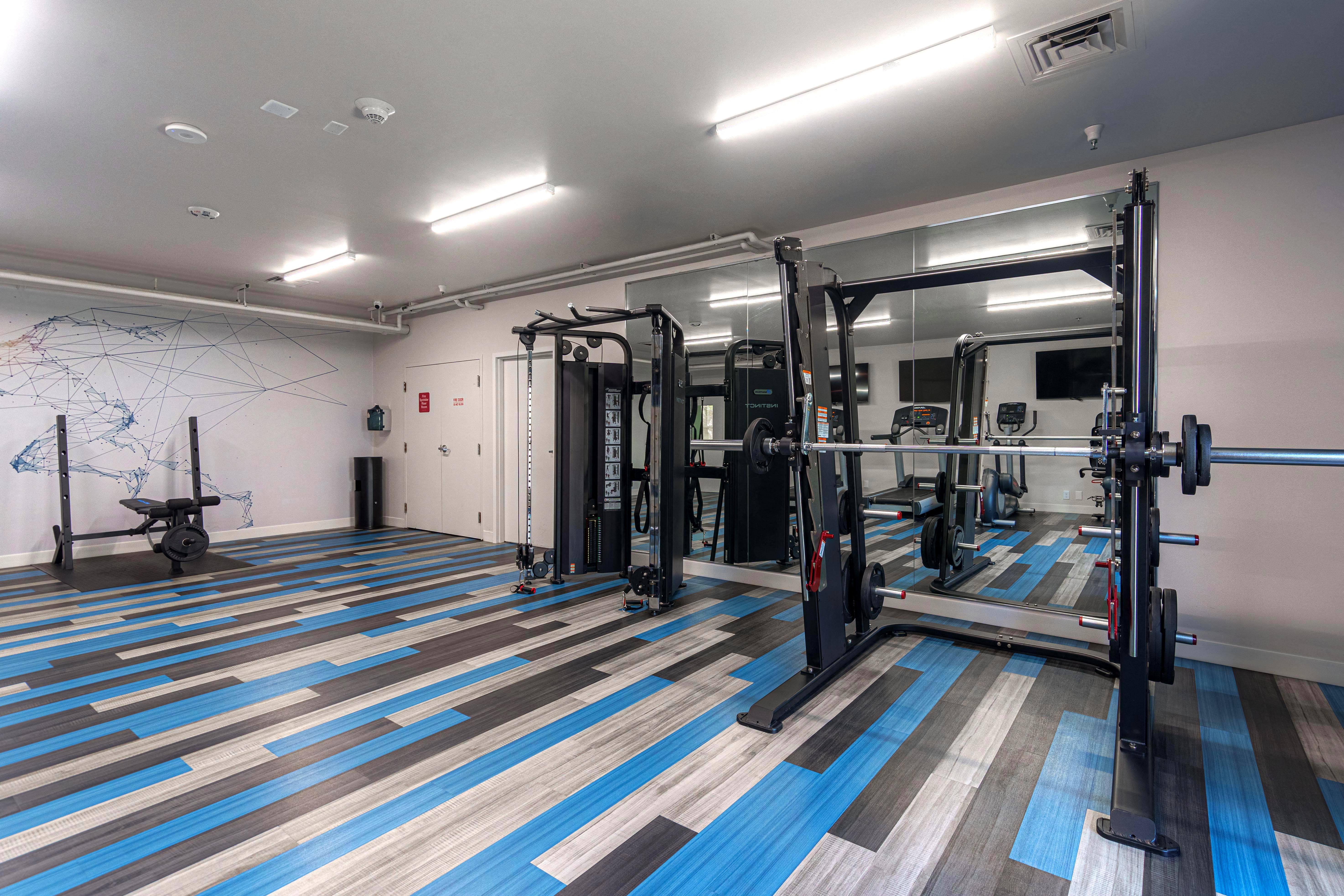 A gym with a blue and brown floor and a white wall with a map on it at AVIA Lofts on Victors Way in Ann Arbor, MI
