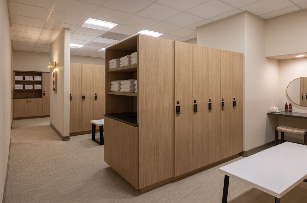 The transition into stillness starts here — warm wood lockers, stacked linens, and a quiet that sets the tone before your first treatment.