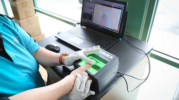 A The UPS Store associate scans the fingerprint of a customer's thumb