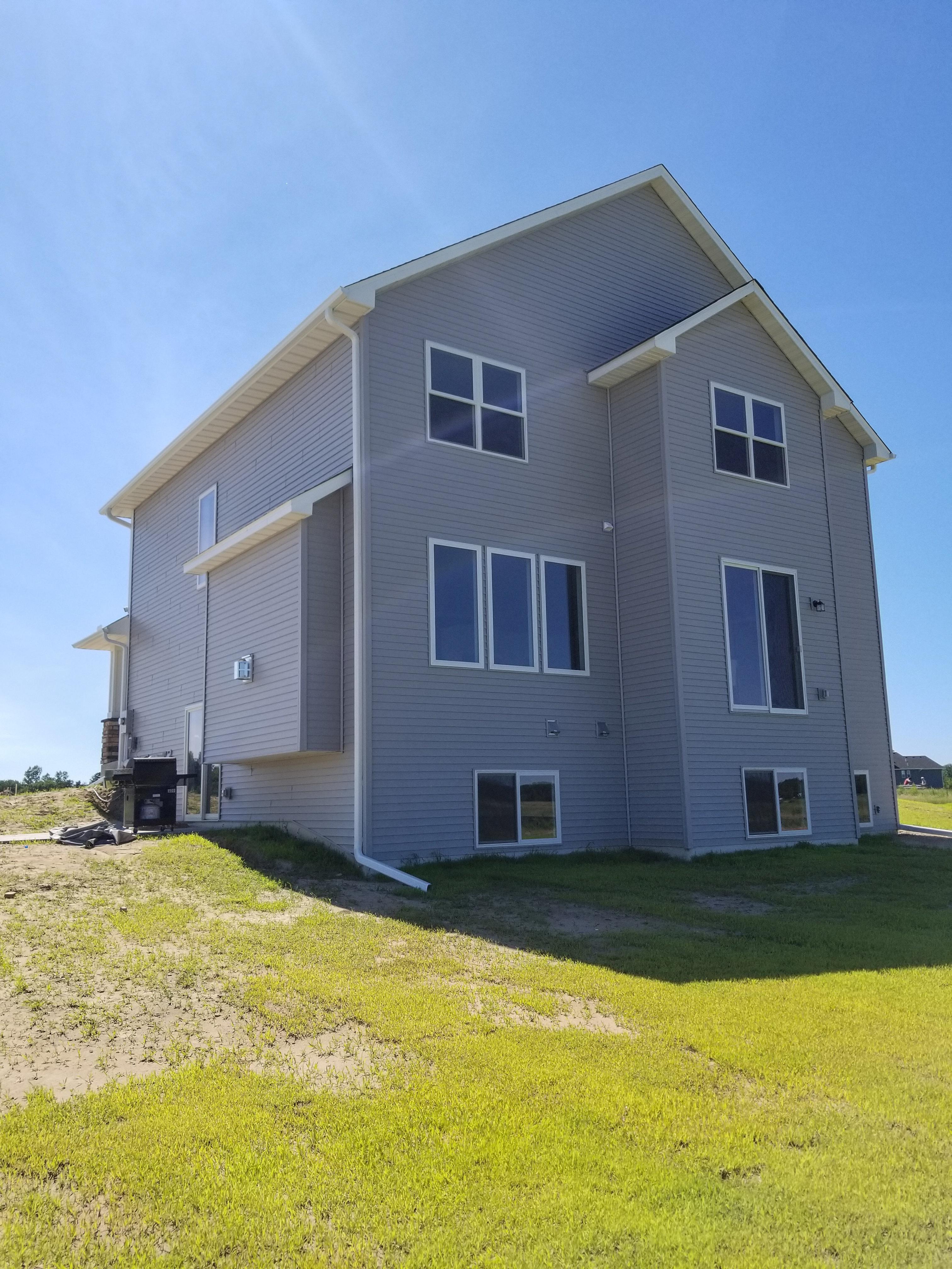 White seamless gutters and downspouts on a two-story grey home by Ultimate Gutter Solutions.