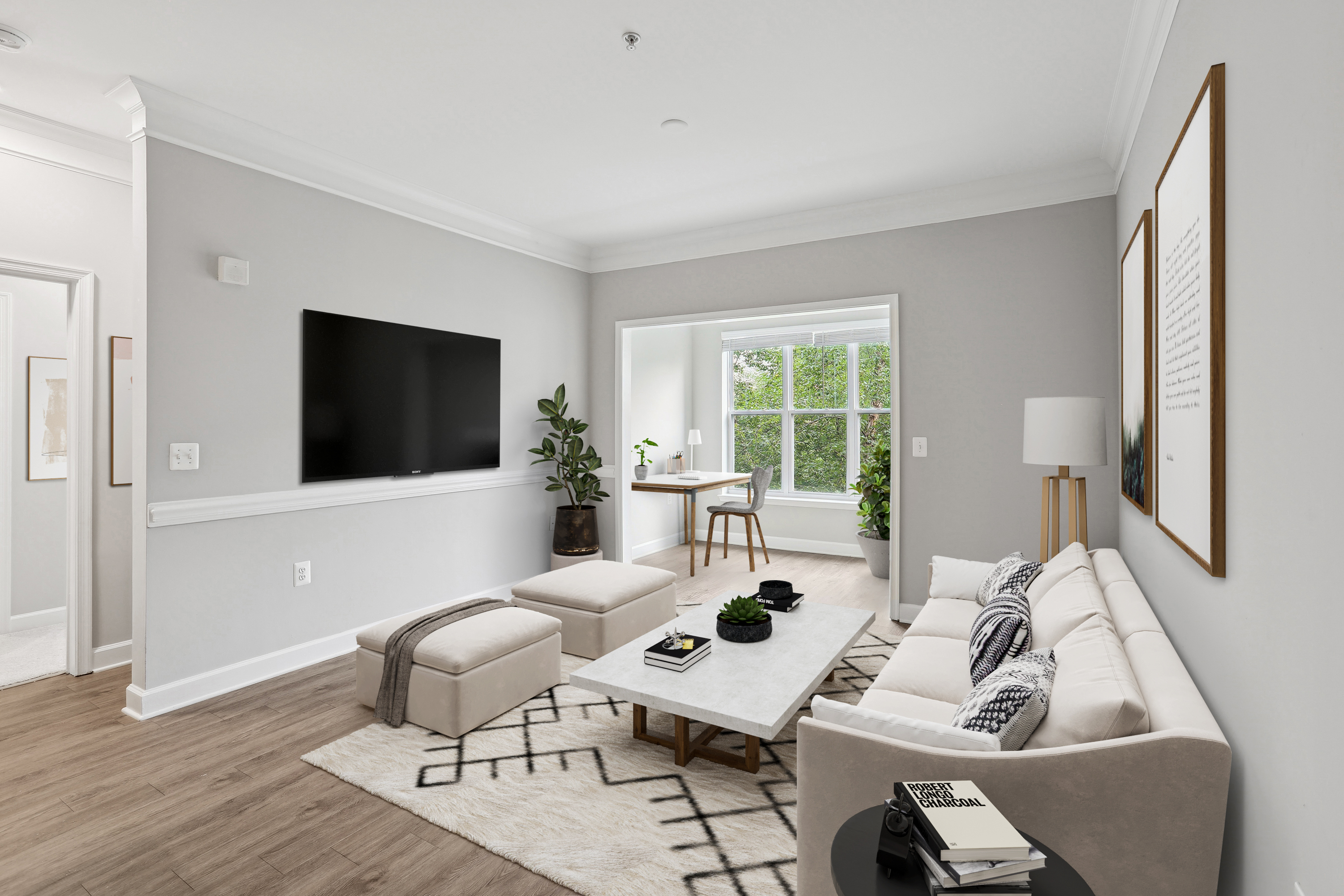 A living room with a white couch, a black coffee table, and a flat screen TV mounted on the wall.