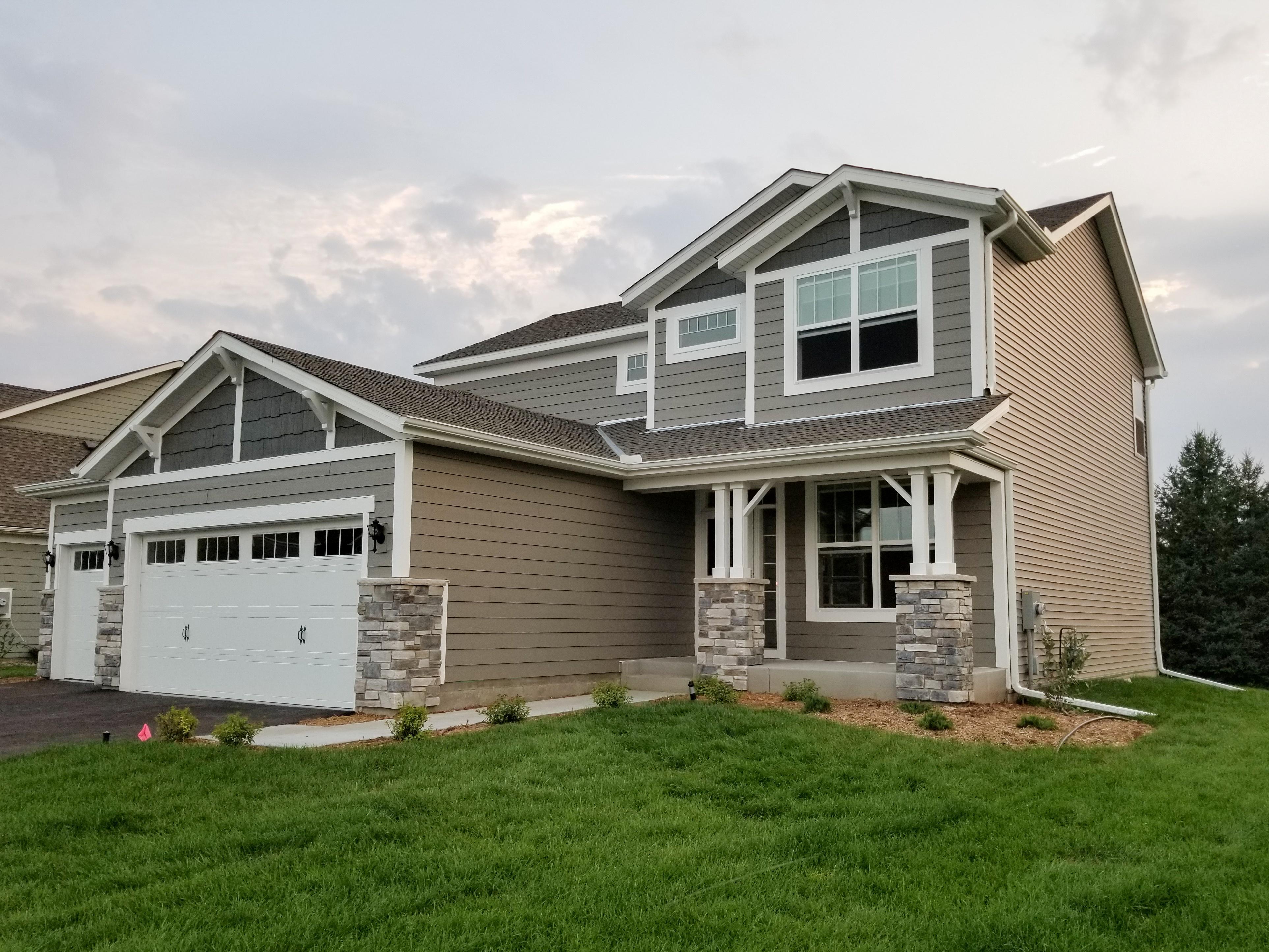 Complete white seamless gutter system and downspouts installed on a modern grey and tan home by Ultimate Gutter Solutions.