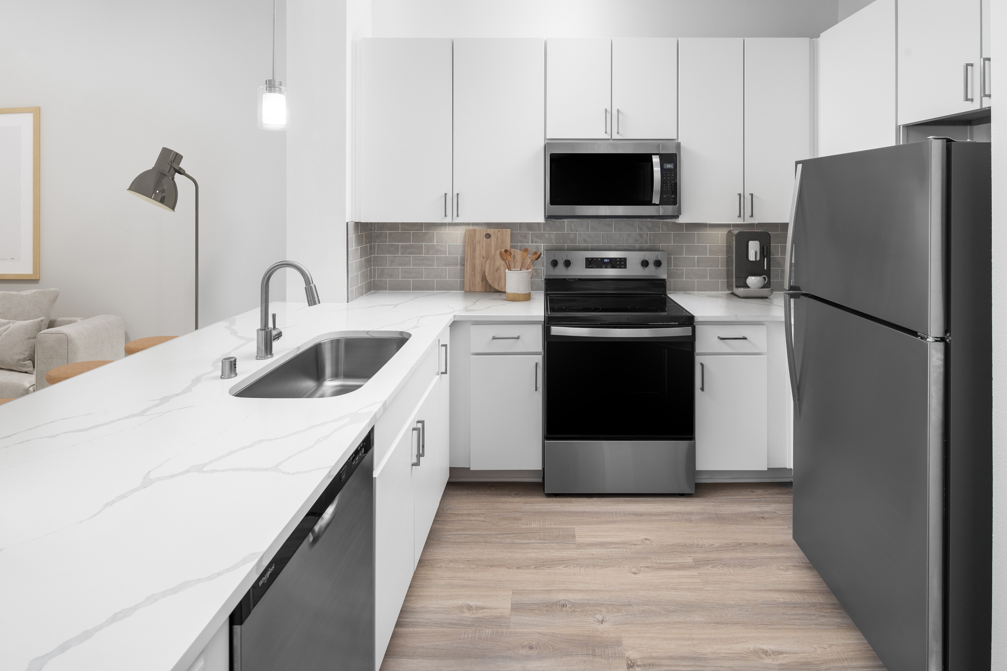 Modern kitchen with white cabinetry, grey subway tile backsplash, white quartz countertops with grey veining and stainless steel appliances at Camden Travis Street in Midtown Houston, Tx