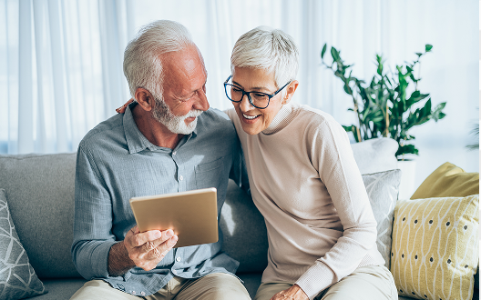 An elderly couple examining a tablet.