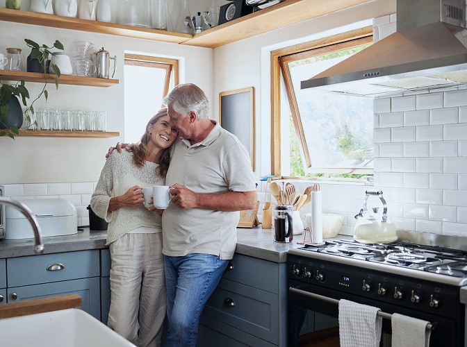 Clients hugging in their kitchen as they share a cup of coffee.