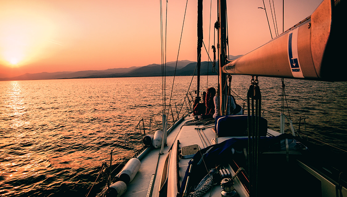 A boat on a smooth body of water at sunset.