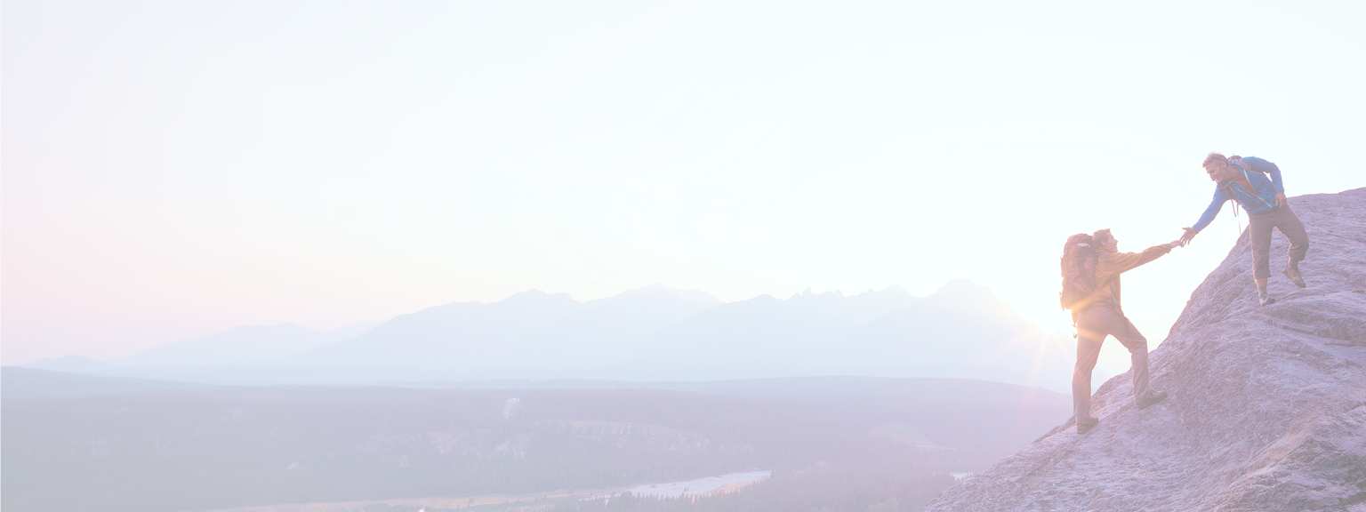 A person lending a helping hand to another person on a mountain hike.