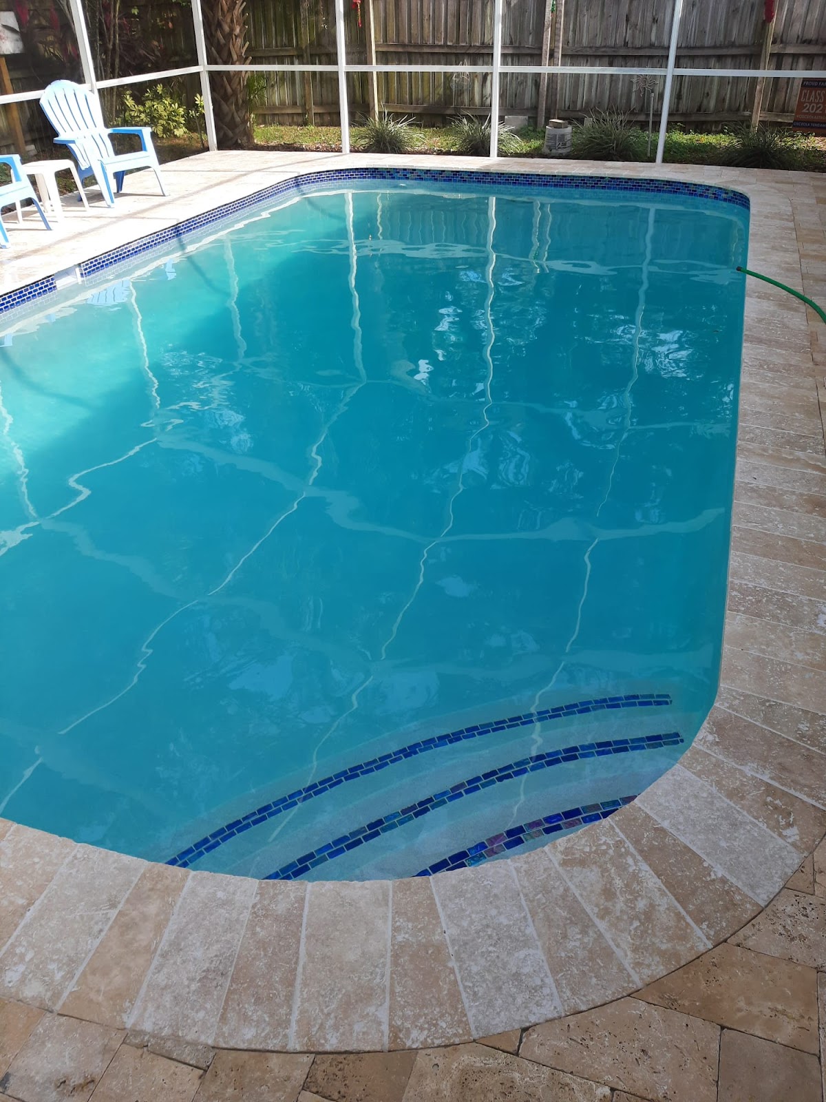 Screen-enclosed residential swimming pool with clear blue water, curved entry steps, and light stone paver decking.
Select 83 more words to run Humanizer.
