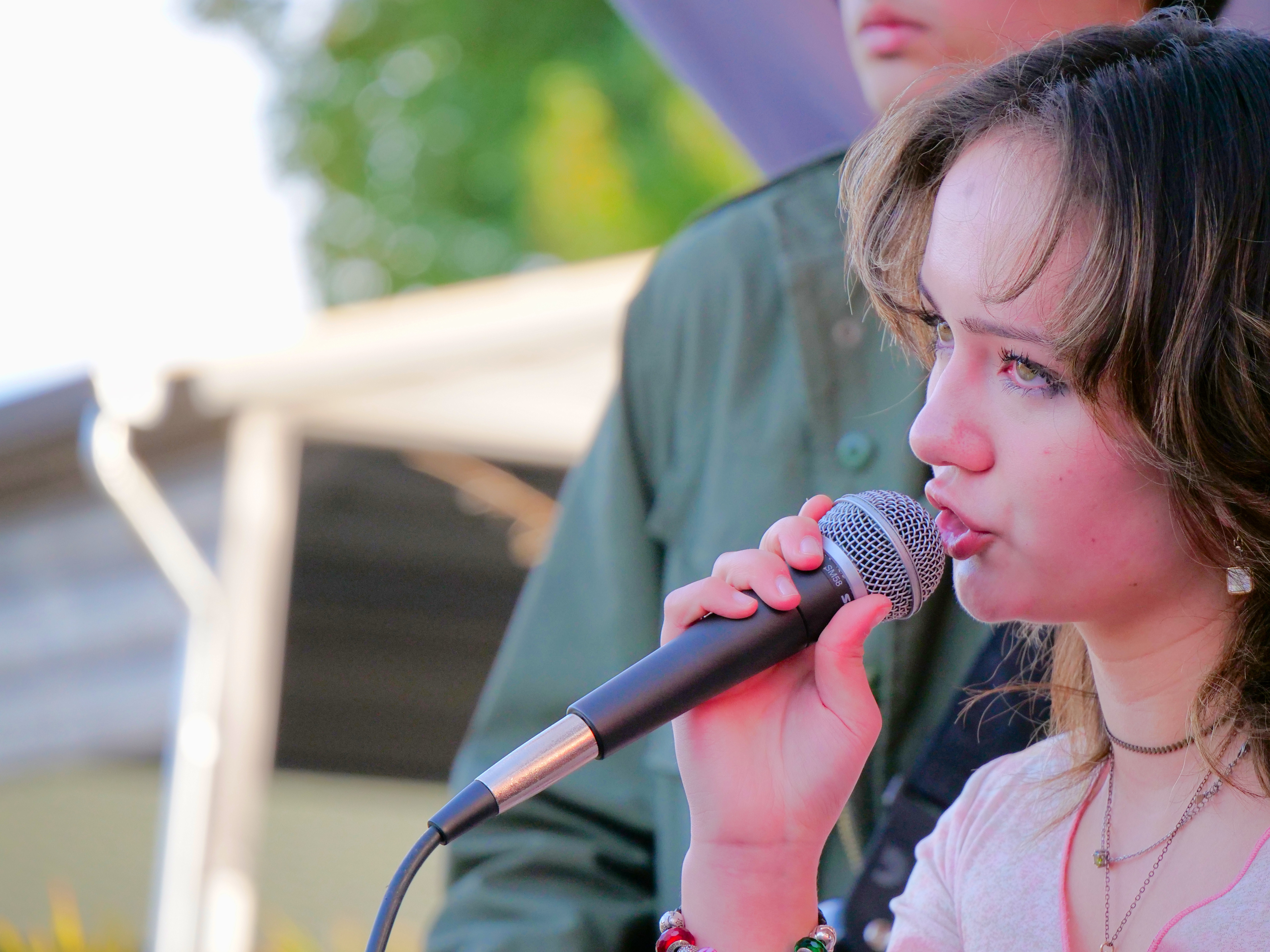 Young vocalist performing live on stage as part of a student music performance program.