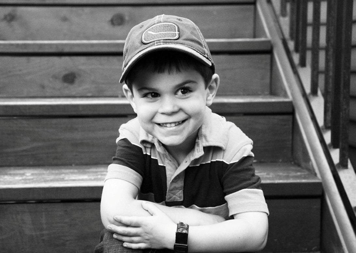 A smiling child sitting on the front steps of a house.