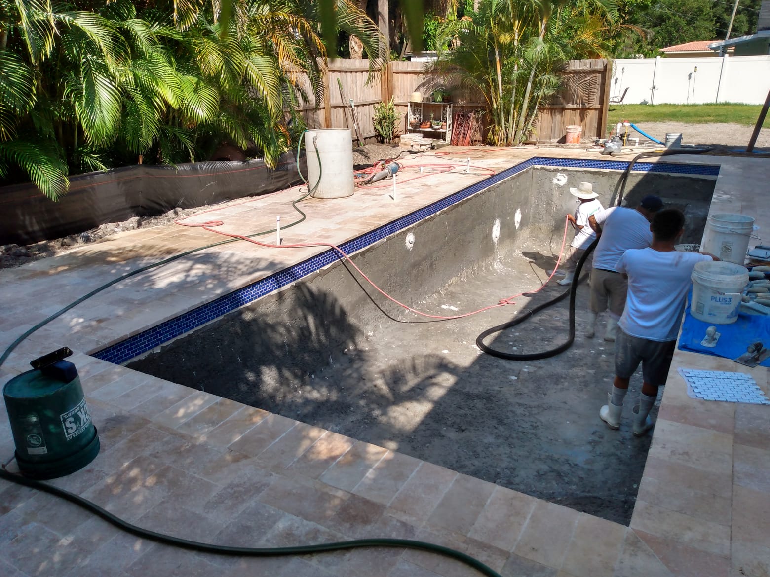 Residential swimming pool renovation in progress with the pool drained and a service professional working on the interior surface.