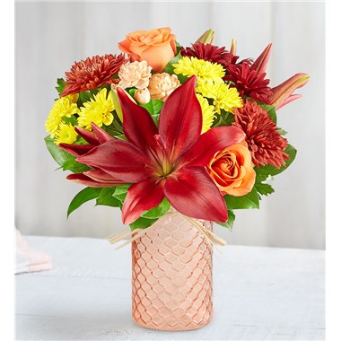 Our colorful bouquet celebrates autumn’s rich beauty. Harvest-toned blooms are loosely gathered with pops of peach for a touch of sweetness. Adding to the charm is our peach quartz mason jar, a textured container designed in a honeycomb pattern and finished with a raffia bow.