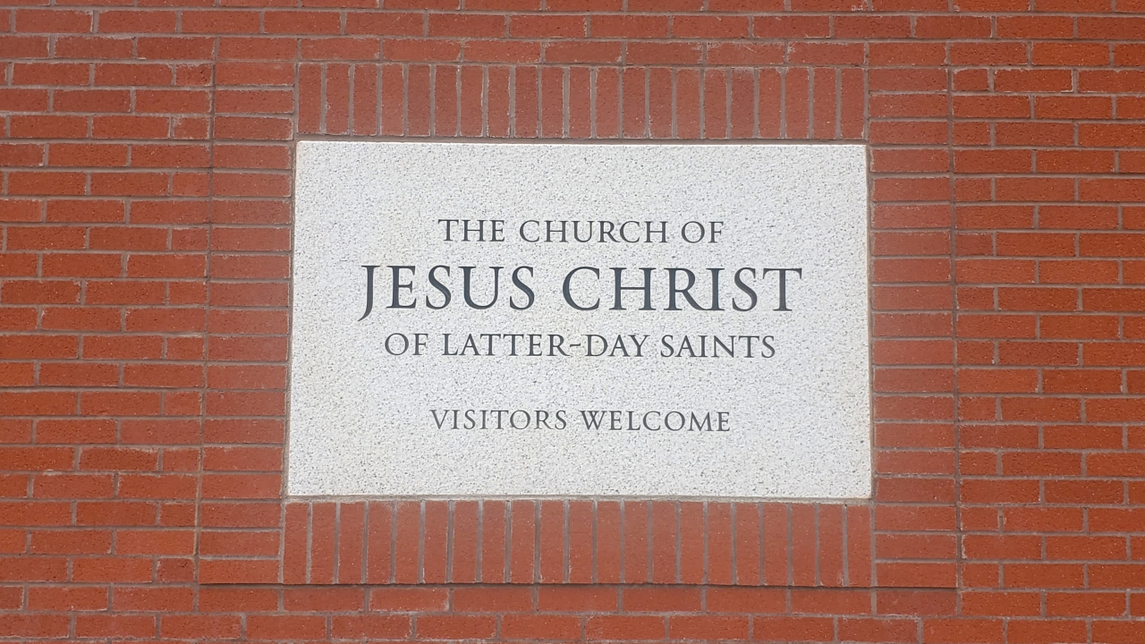 Sign on front of the building which reads, "THE CHURCH OF JESUS CHRIST OF LATTER-DAY SAINTS VISITORS WELCOME"