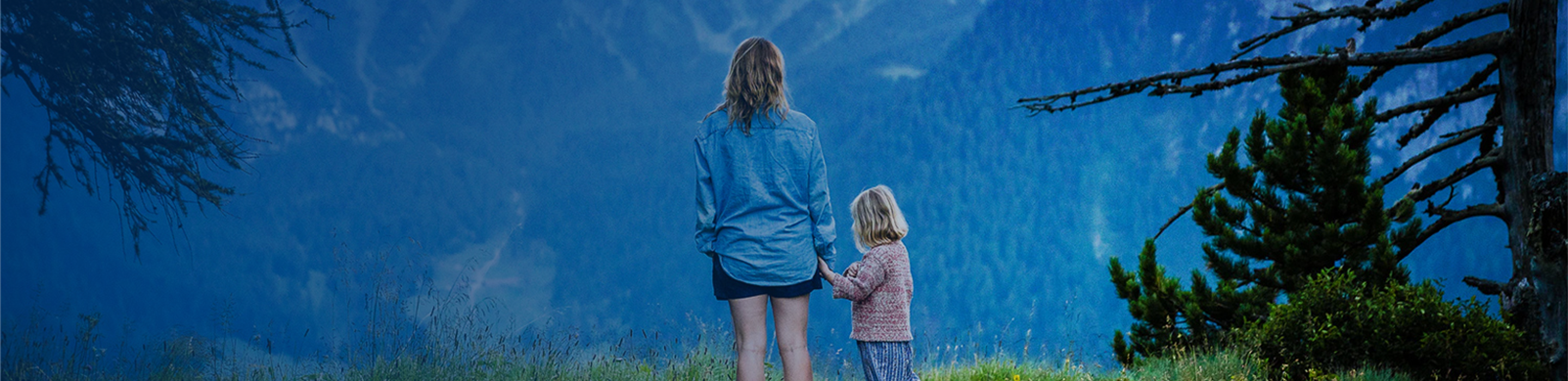 A mother and young daughter taking in the view of the mountains from a lookout point.