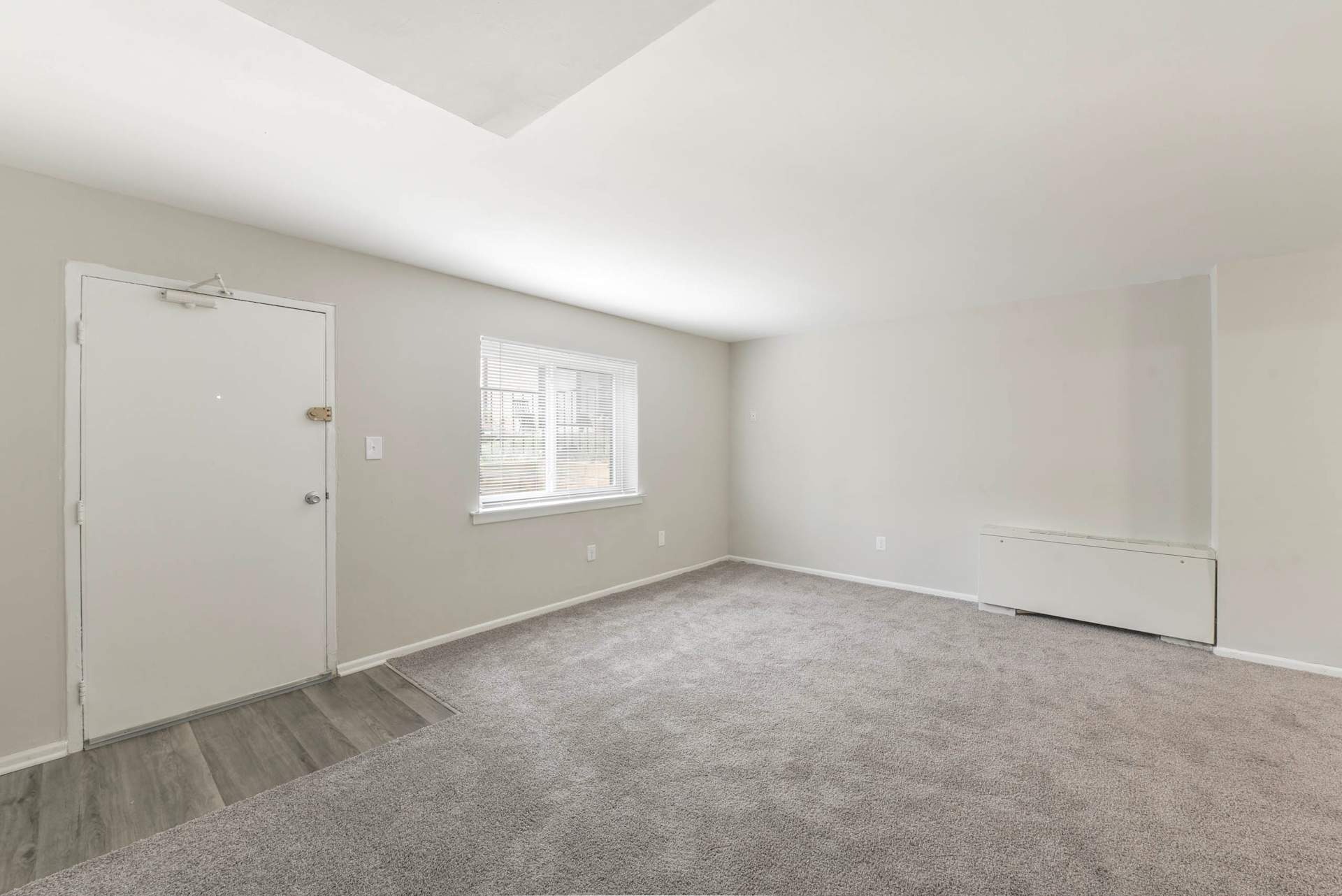 A room with a carpeted floor and a window.