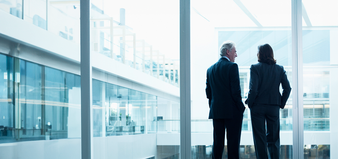Deux personnes debout près d’une fenêtre de bureau.