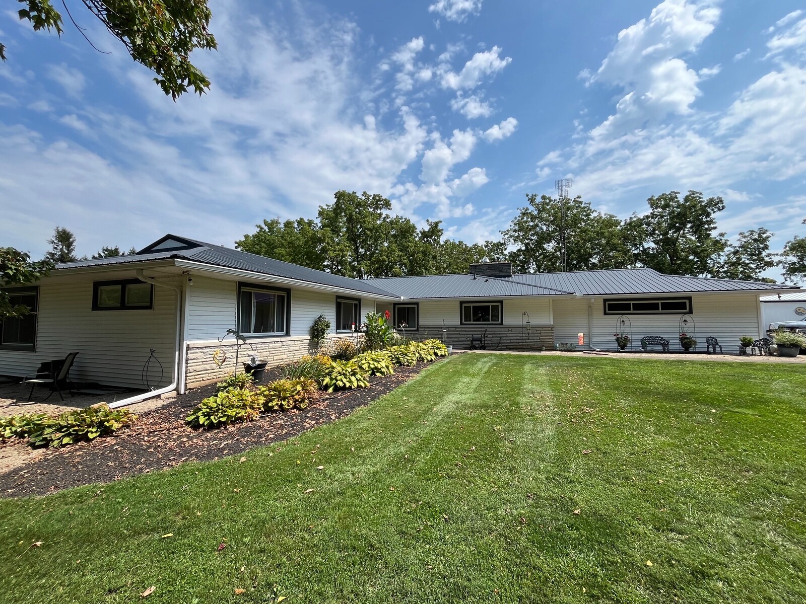 Completed metal roof installation shown across the landscaped rear courtyard of a residence.