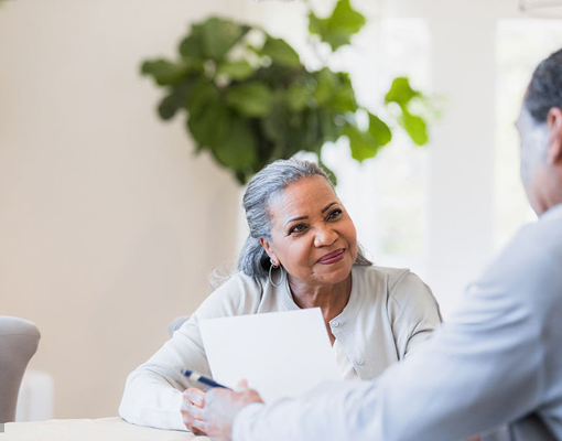 A client smiling while her advisor presents a document to her.