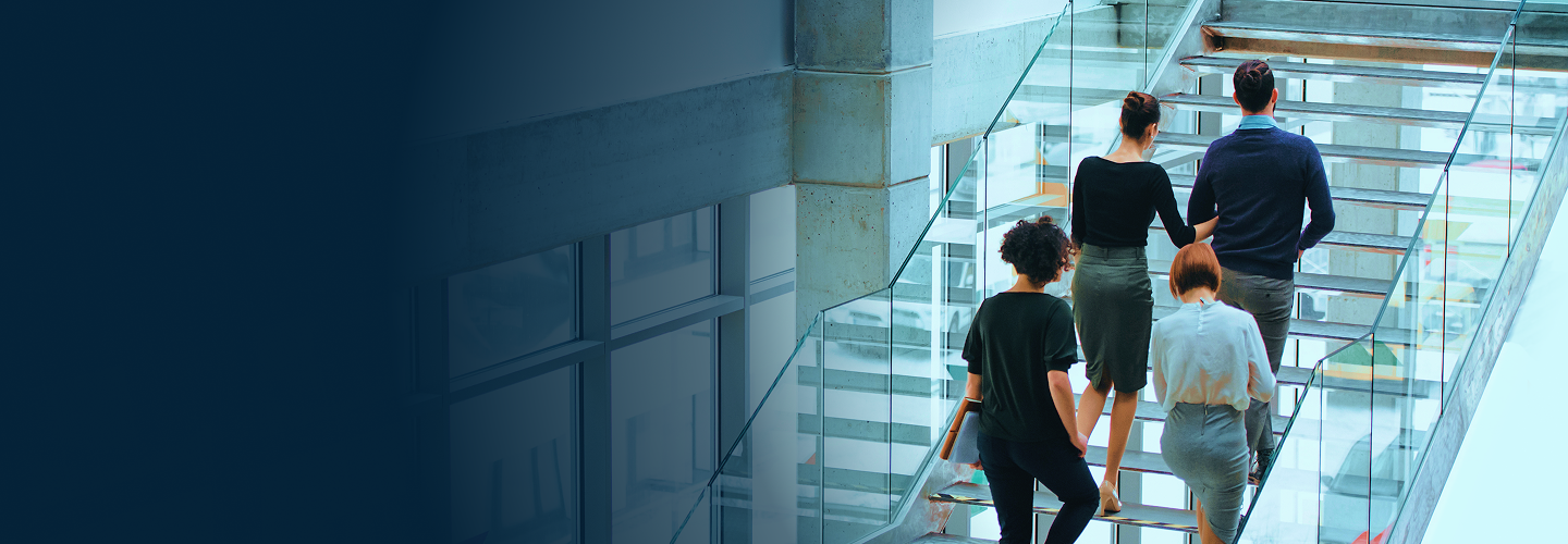 A team of professionals walking up stairs in a bright, modern office building.
