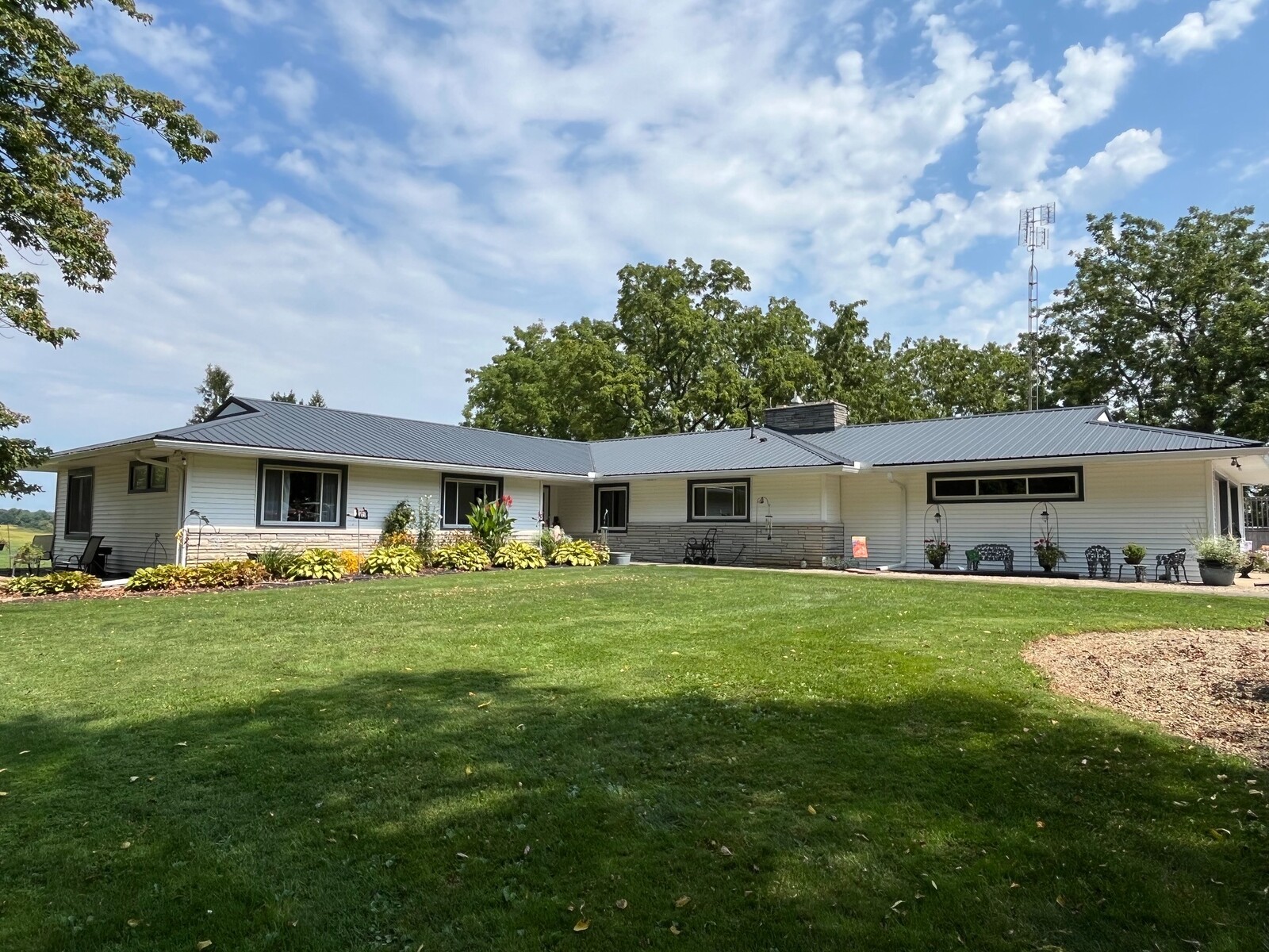 Wide view of a completed dark metal roofing system on a single-story residential property.