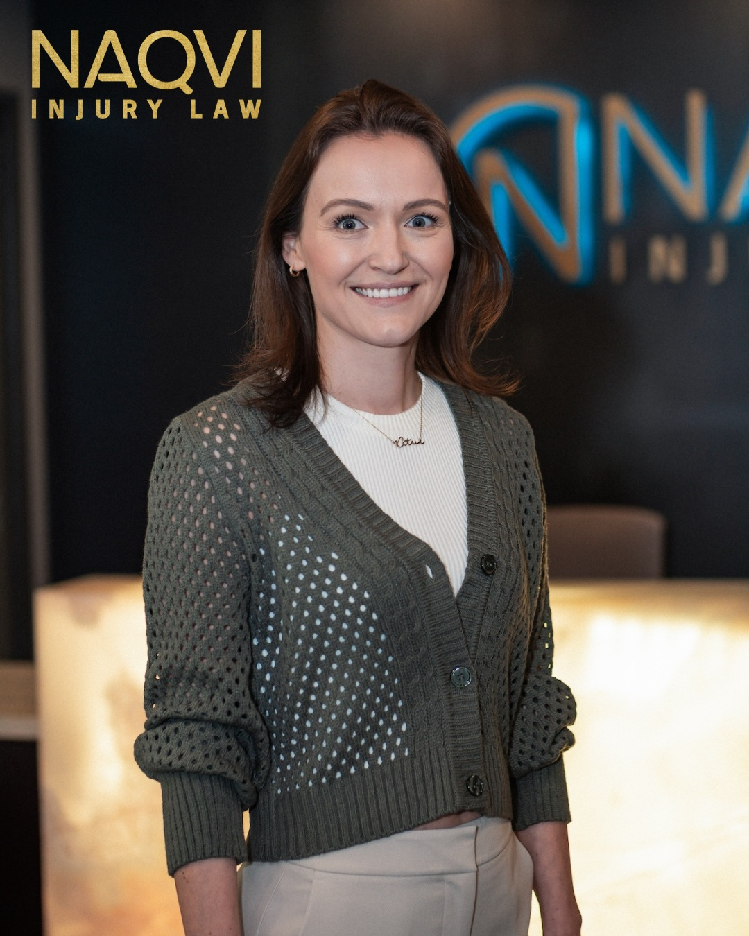 Naqvi Law team member smiling in front of desk