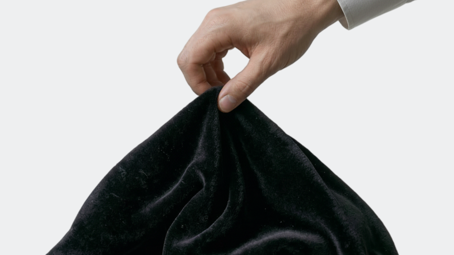 Hand lifting a black cloth to reveal something hidden, representing uncovering hidden competitors in local search.