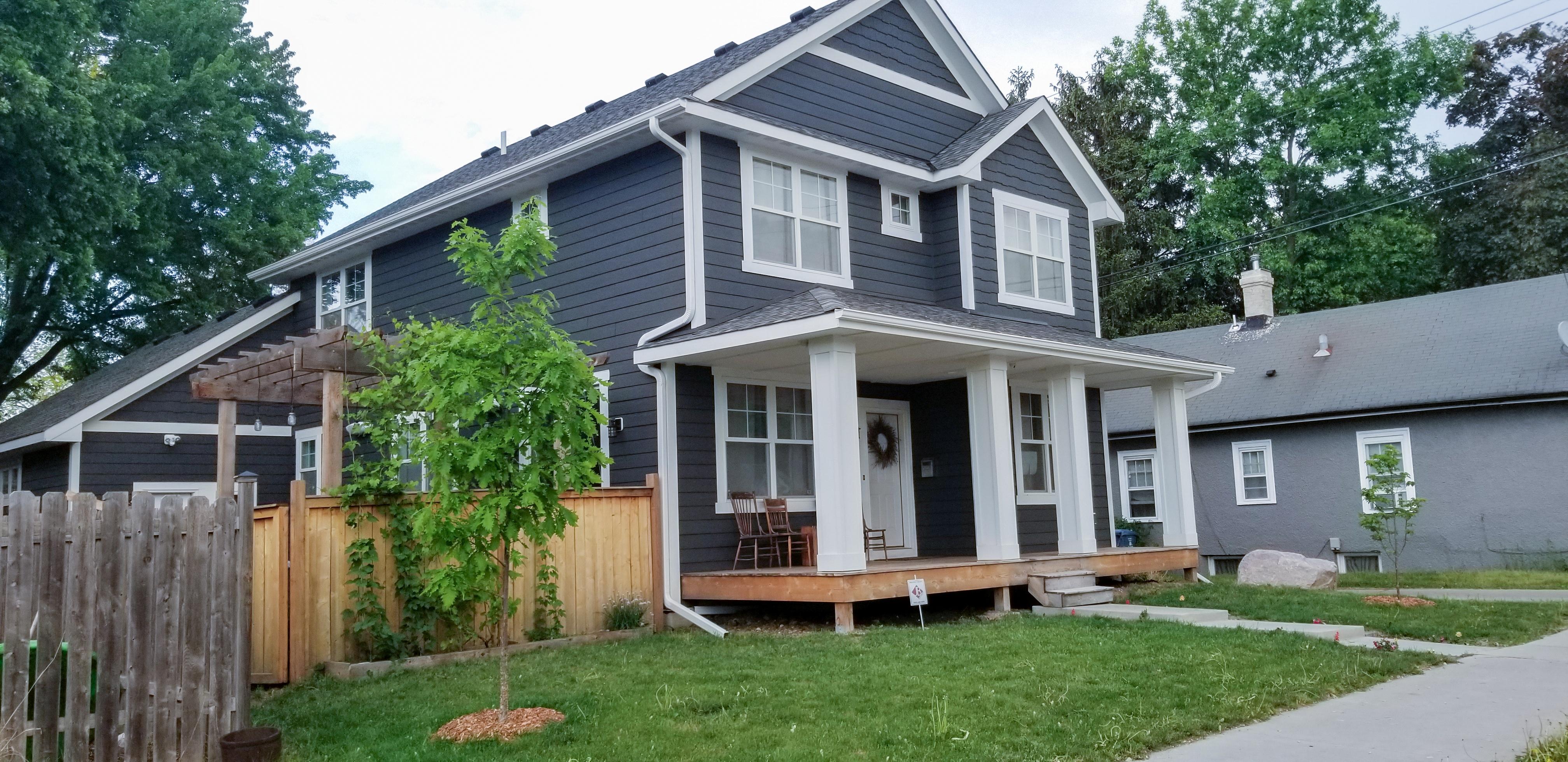 Bright white seamless gutters and downspouts installed on a dark grey home by Ultimate Gutter Solutions.