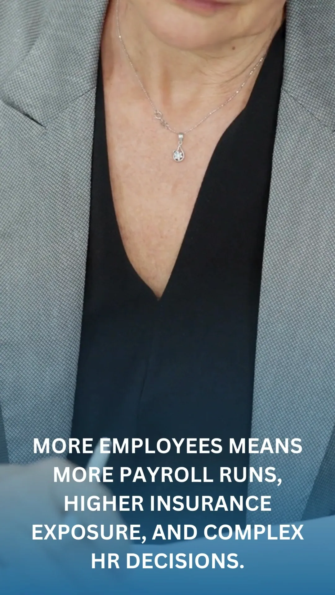 A close-up shot shows a person wearing a grey blazer over a black top. A delicate silver necklace with a small, clear pendant is visible around their neck. Text overlay on the lower portion of the image reads: "MORE EMPLOYEES MEANS MORE PAYROLL RUNS, HIGHER INSURANCE EXPOSURE, AND COMPLEX HR DECISIONS."