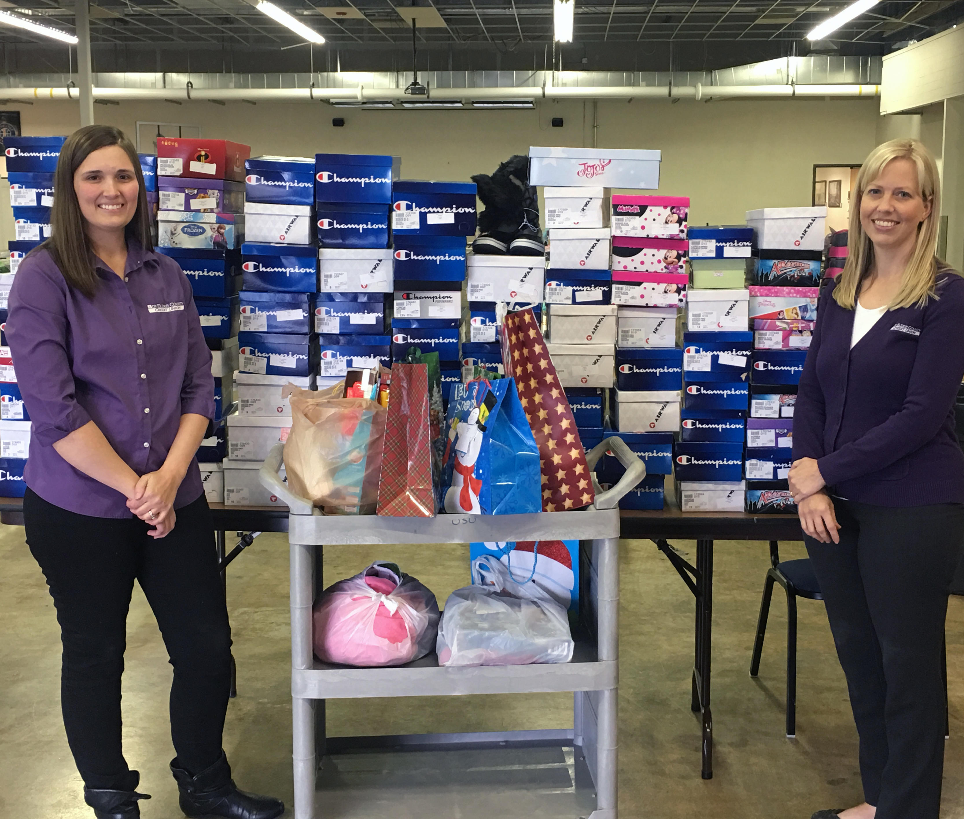 Two employees giving shoes and blankets for our 65 year anniversary