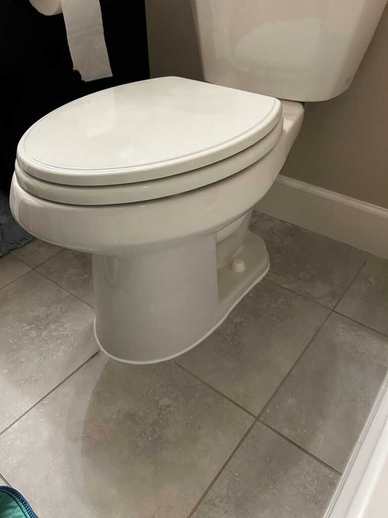 Close view of a clean white residential toilet installed on light gray tiled flooring against neutra 