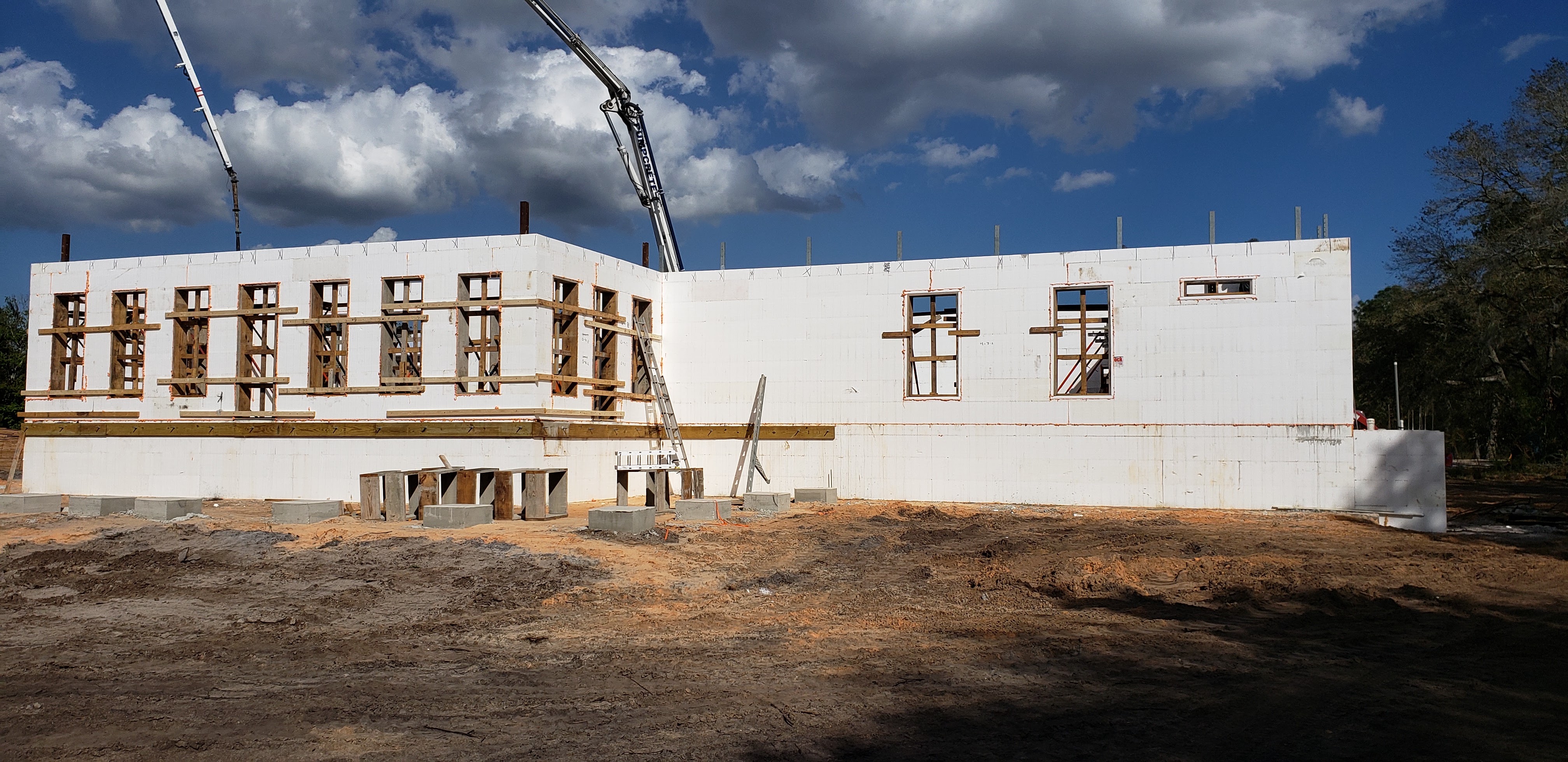 A construction site shows a building made of white insulated concrete forms (ICFs) with wooden frami 