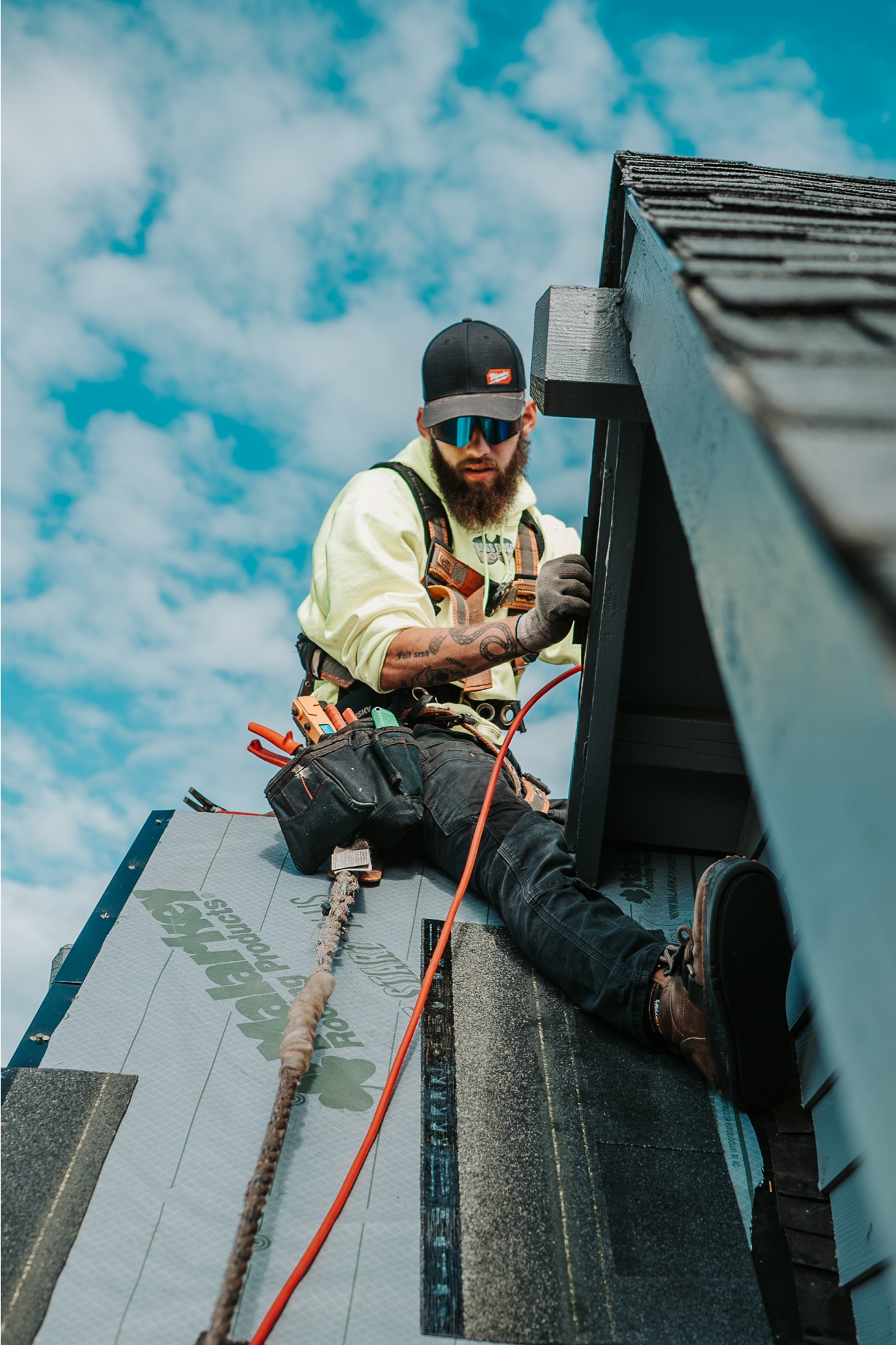 Roofer working safely on a steep residential roof using fall-protection equipment. 