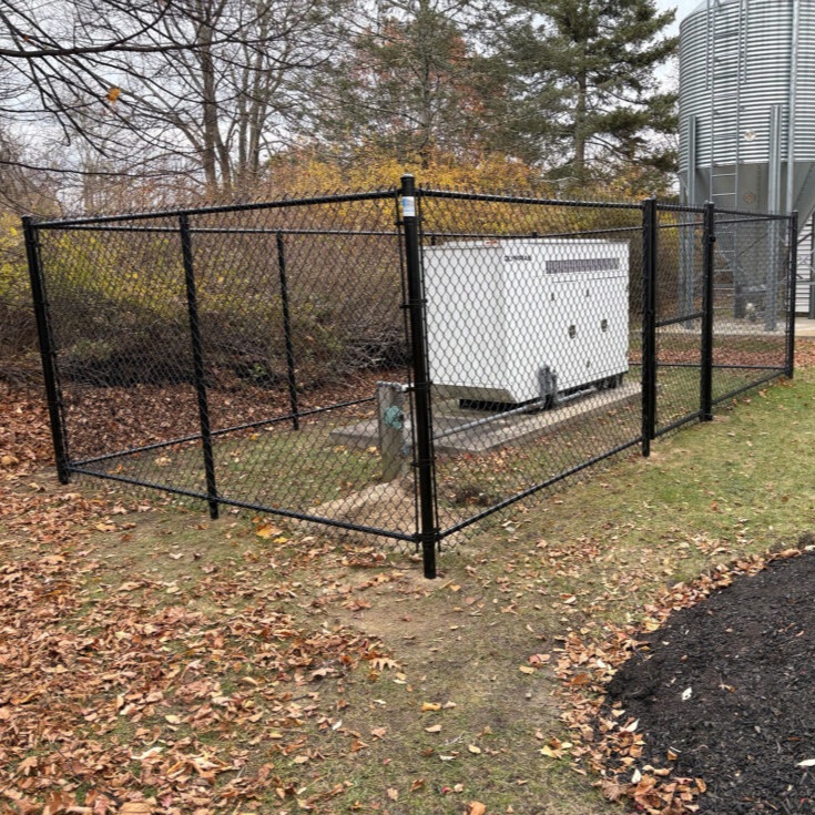 Granite State Fence completed this 6&prime; High Black Chain Link Fence installation in Hollis, NH, enclosing a commercial generator for added security and protection.