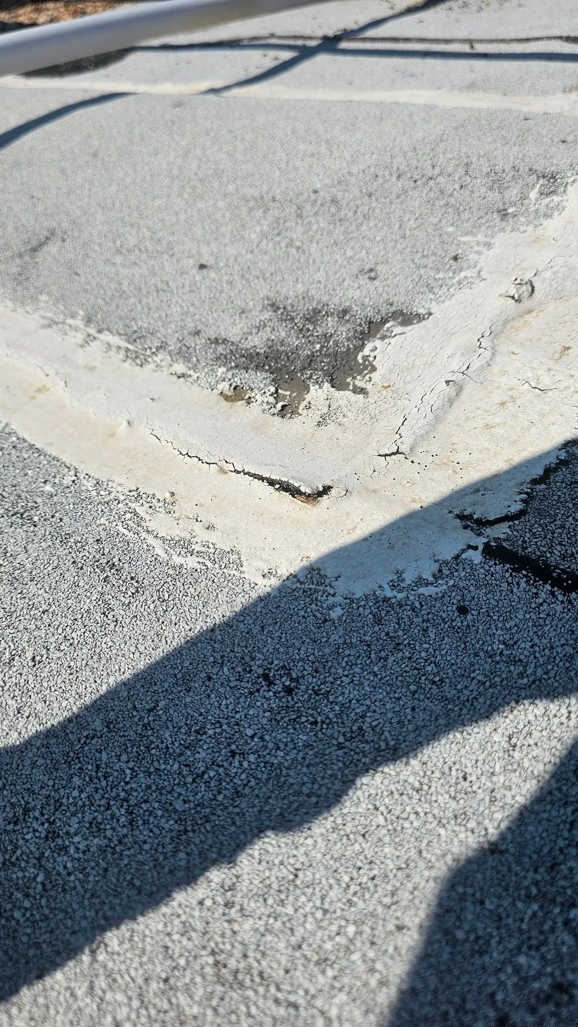 Cracked commercial roof membrane displaying weather-related deterioration and coating failure, highl 
