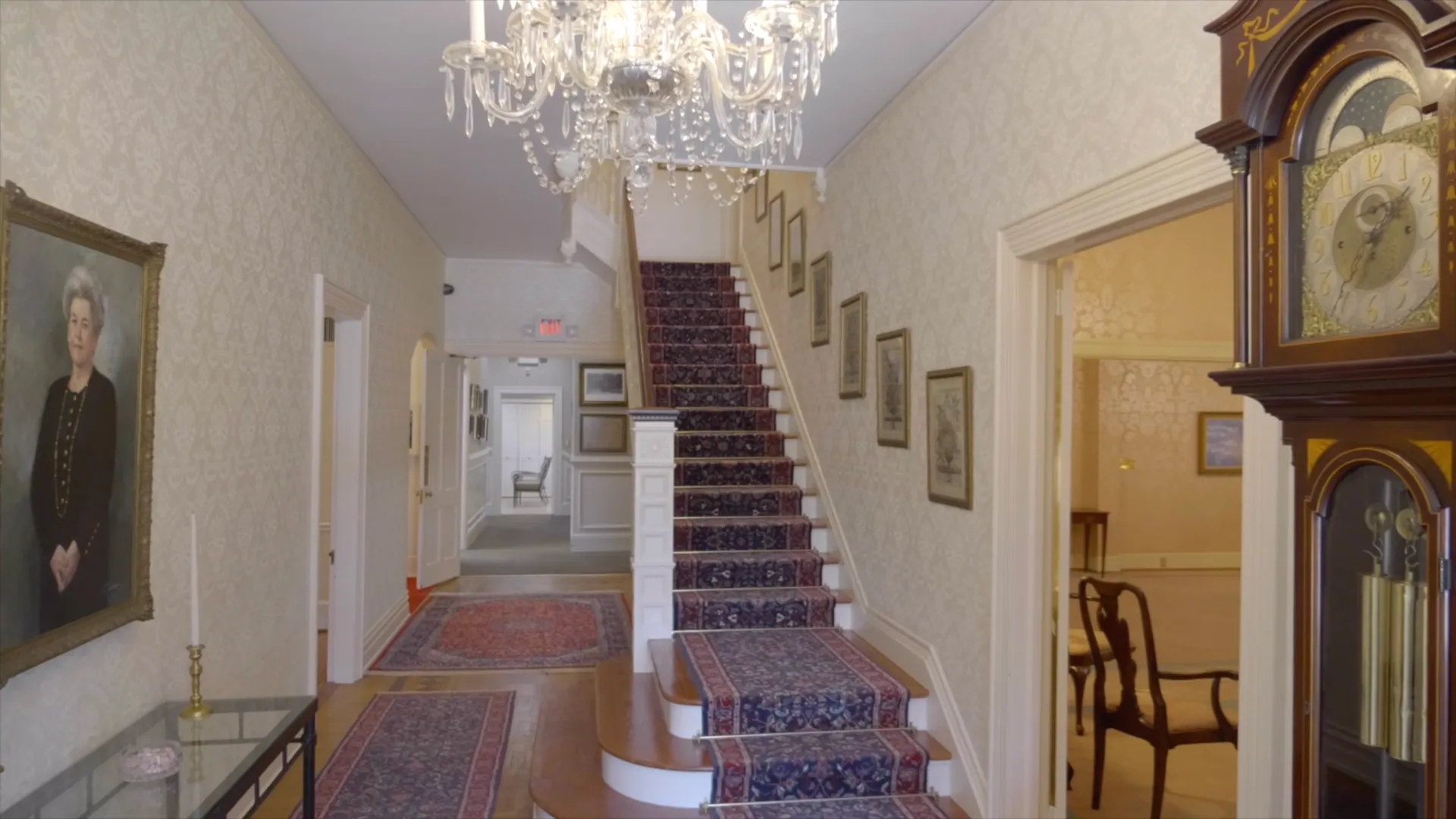 The grand hallway inside Platt's historic Augusta location, with a curved staircase, chandelier, and 