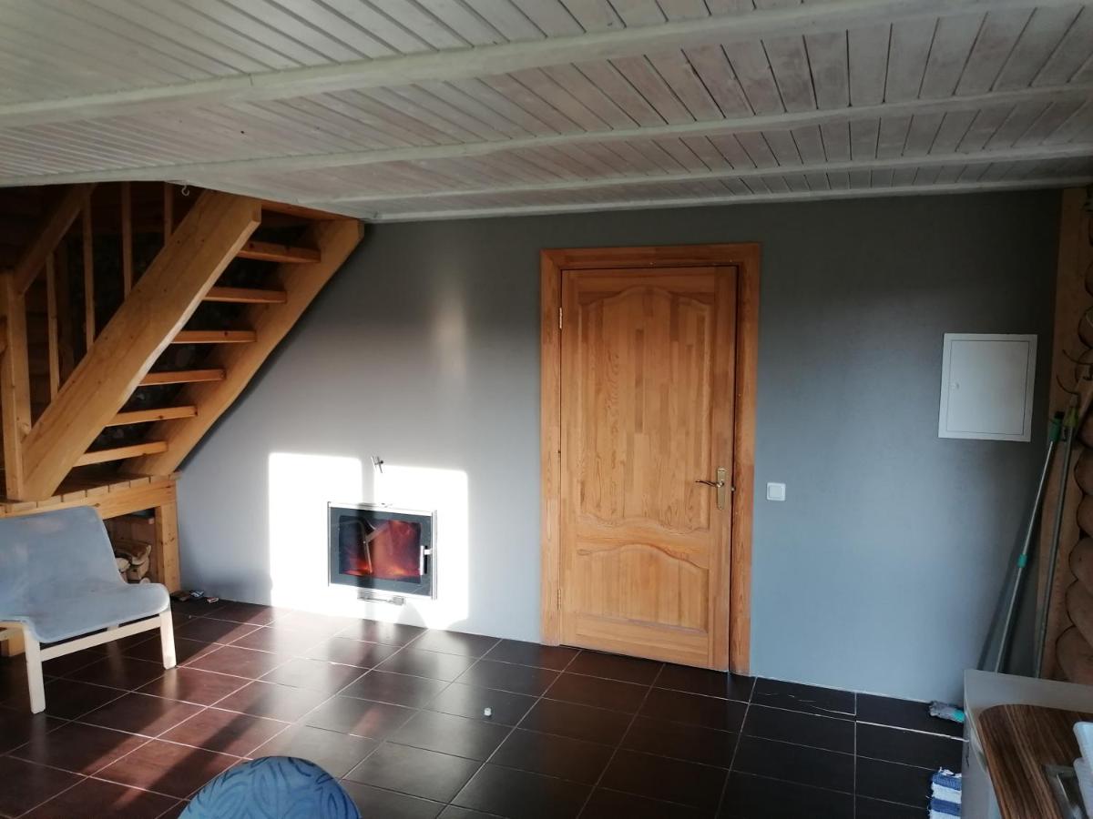 Gaiša un mājīga guļamistaba viesu namā 'Palmas' ar komfortablu gultu, koka detaļām un logu ar skatu uz dabu.