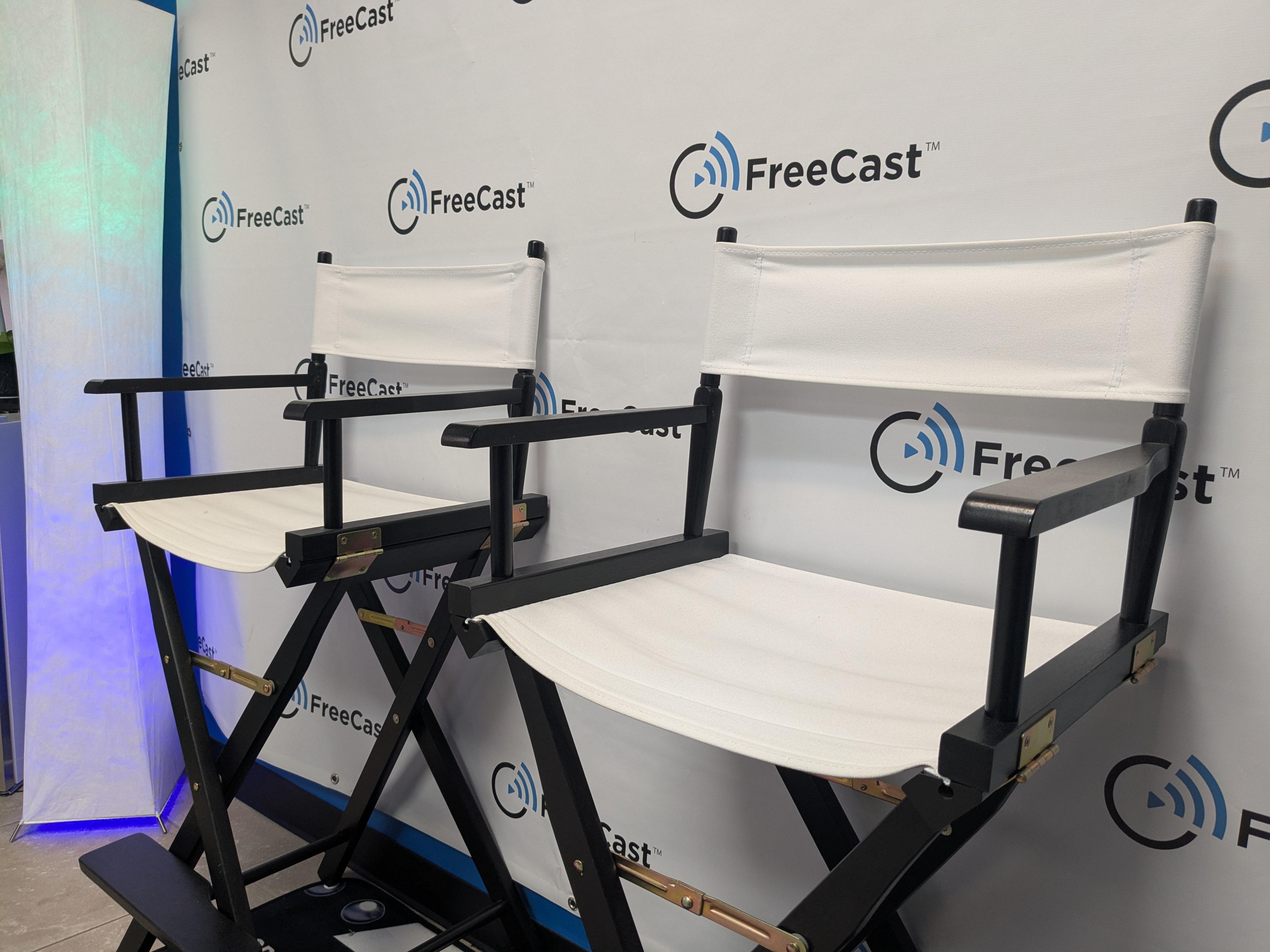 A professional interview and media production setup at FreeCast, Inc., showcasing two stylish white director’s chairs positioned in front of a branded FreeCast backdrop.