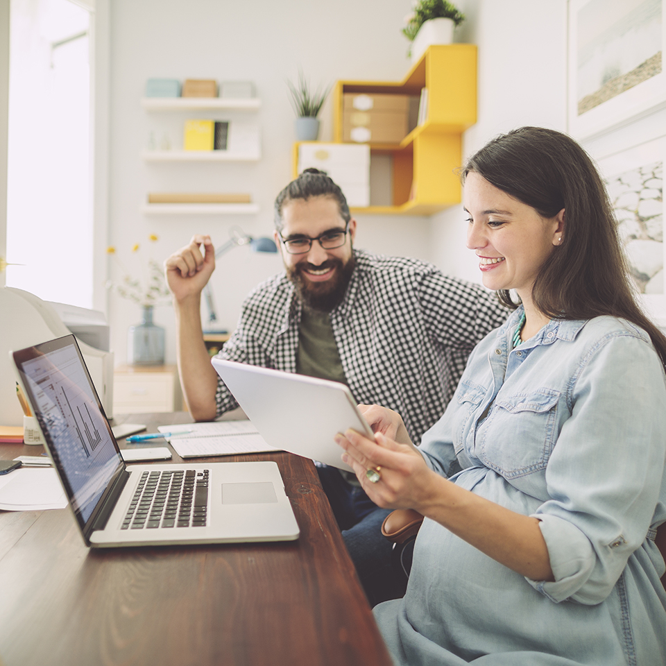 Man and woman sitting at a desk looking at a computer