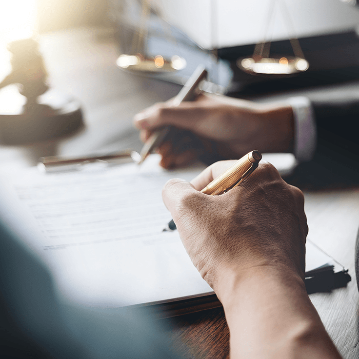Close-up of someone signing documents on a clipboard.