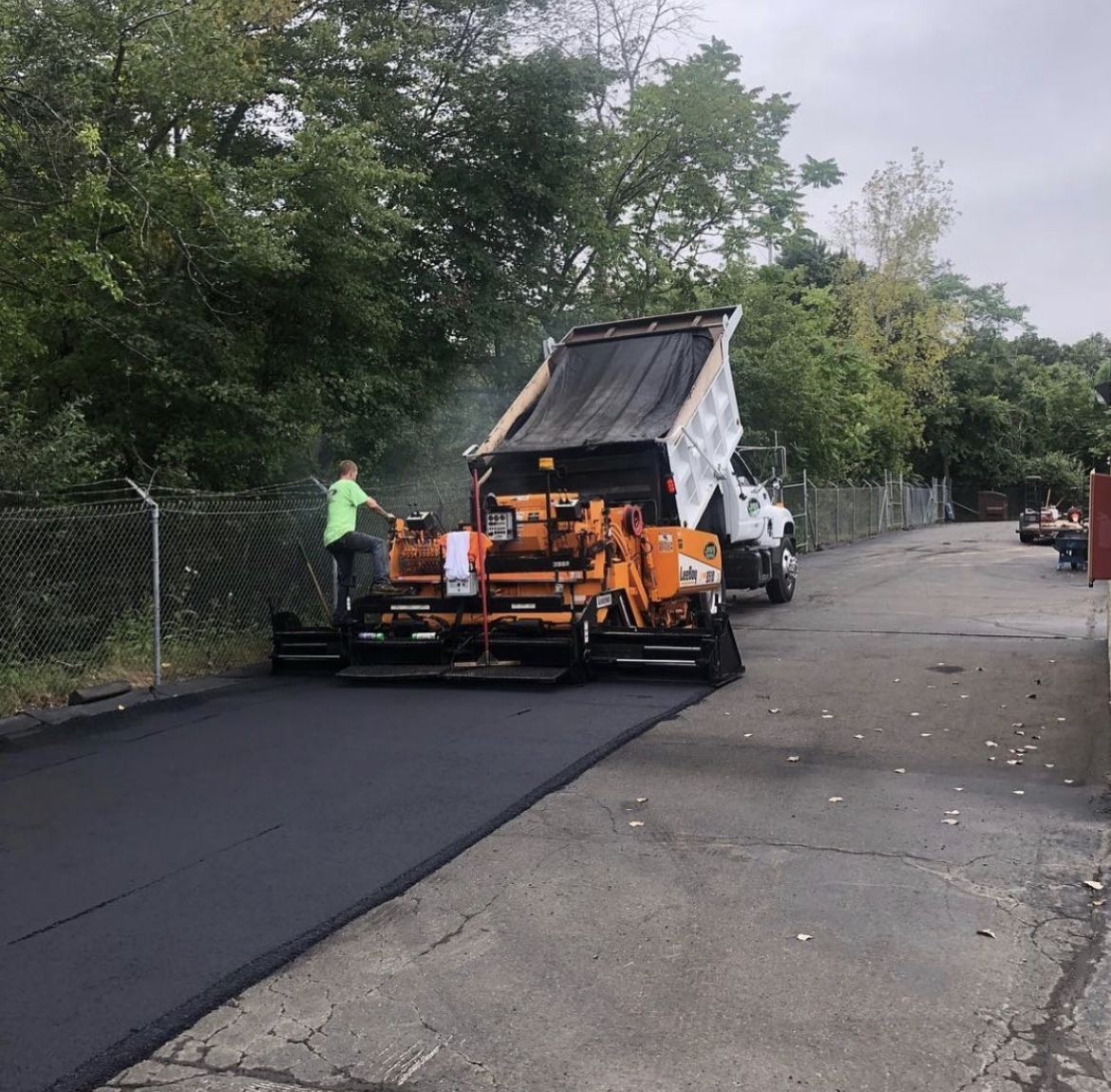 Asphalt paver in action on a commercial paving project, specializing in parking lot paving and large-scale asphalt installation in Maine.