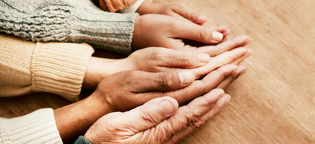 A close-up of a multigenerational family's hands on a table.