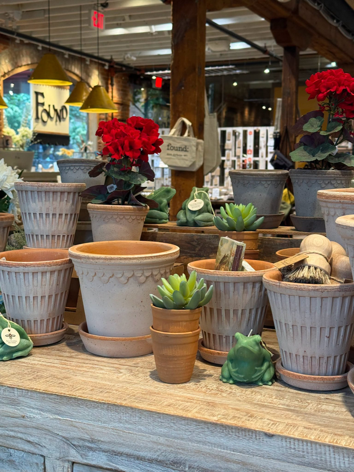 Decorative pots and planters displayed with colorful flowers, succulents, and indoor plants at FOUND 