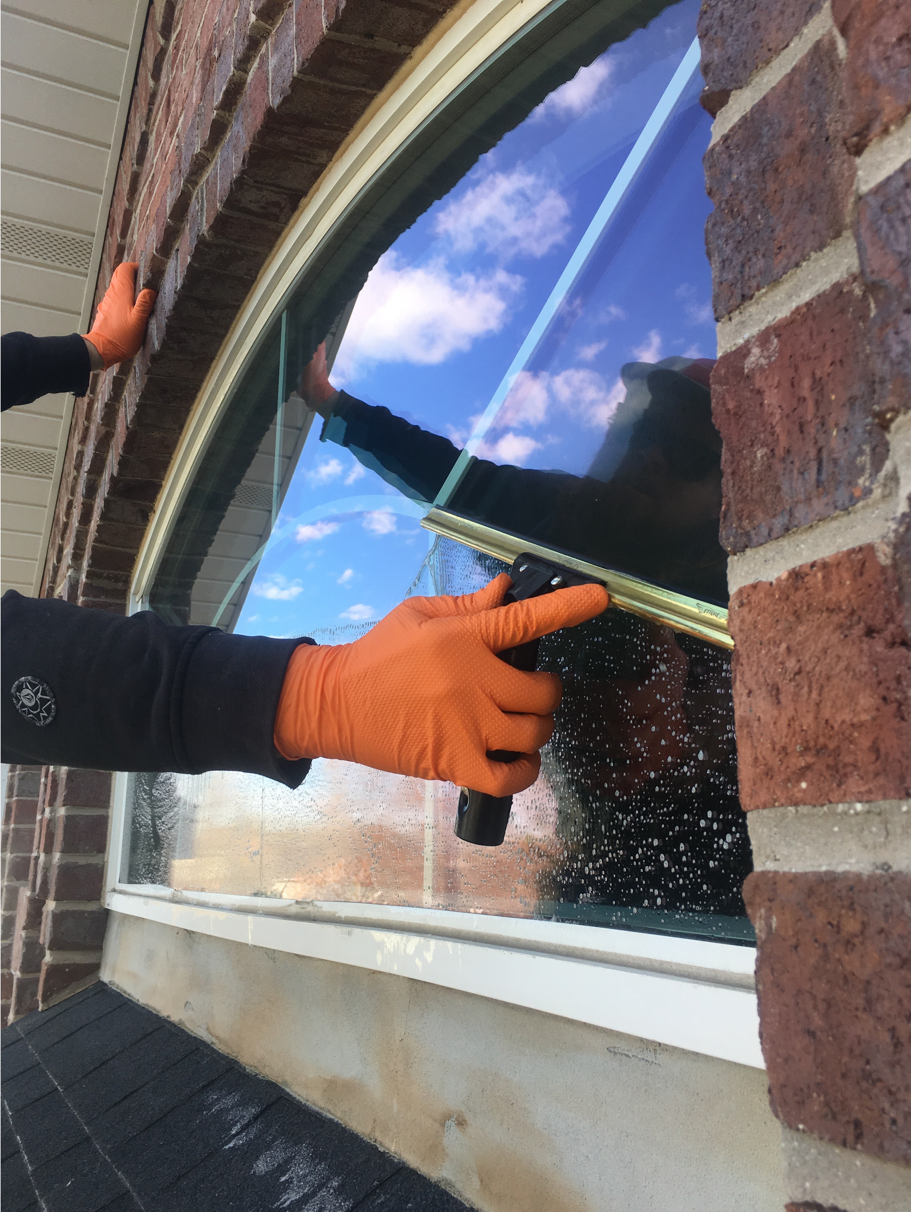 Window being cleaned by hand with a squeegee.