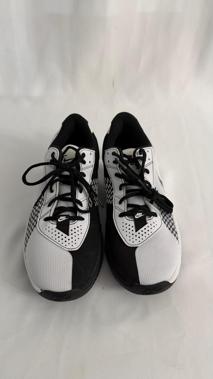 A pair of black and white Nike athletic shoes are shown from a front-facing perspective against a plain white background. The shoes are laced with black laces. A small black Nike logo is visible on the tongue of each shoe.