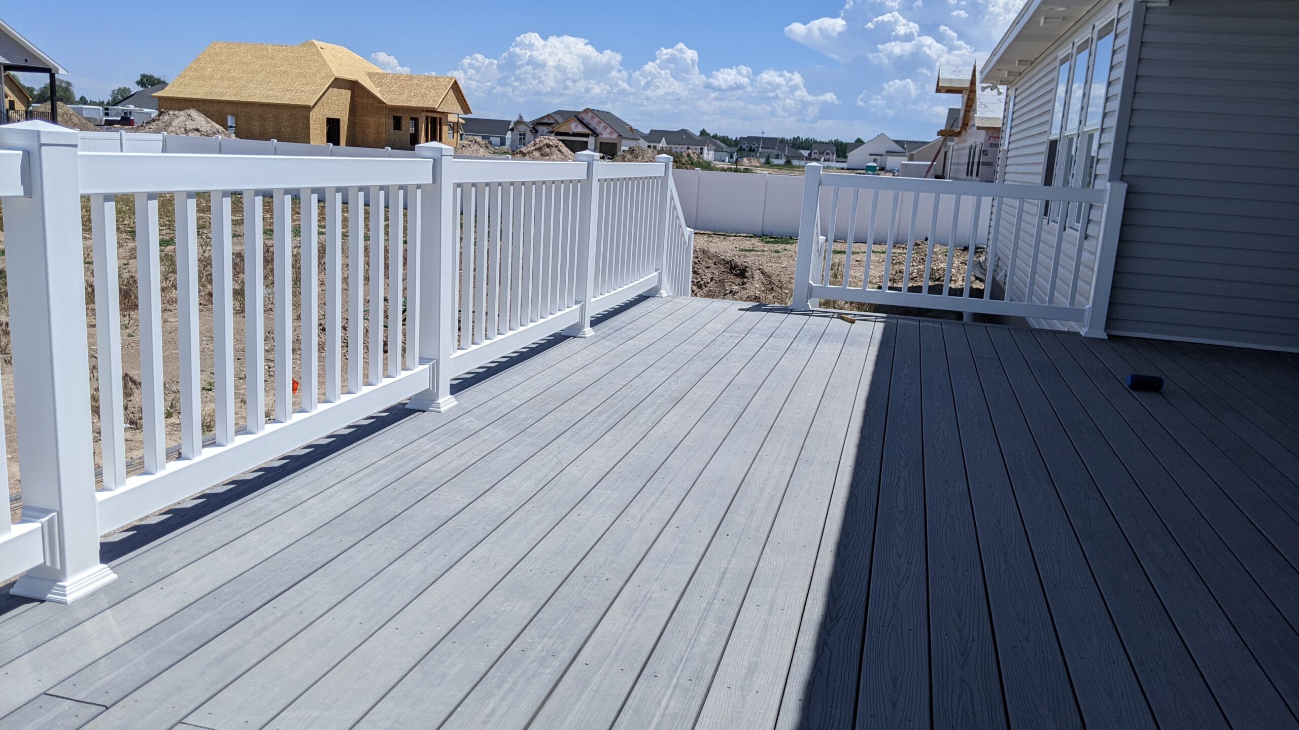 Expand your outdoor living possibilities with this custom composite deck by DeckPro LLC. This design provides a safe and stylish transition from your home to your backyard, even in snowy conditions, thanks to durable, low-maintenance composite materials. We included a unique railing system that combines clean white posts with a striking horizontal louvered privacy wall on one end, creating a cozy and inviting retreat.