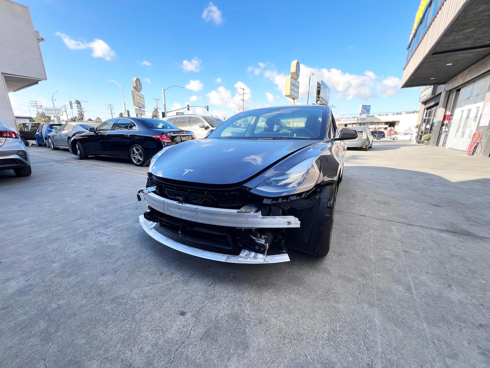 Detailed photo of Tesla Model 3 waiting at auto body shop parking lot for collision repair